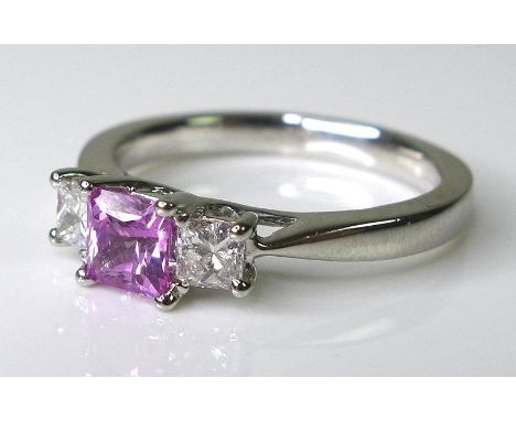 A platinum, pink sapphire and diamond ring, the central emerald cut sapphire of approximately 0.6ct and flanked by two emeral