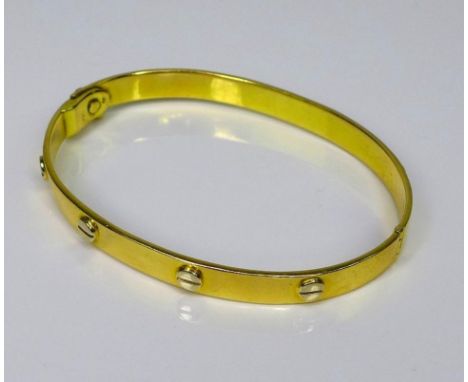 A Cartier style 18ct gold screw head bangle, the hinged arms of the bangle each with four screw head motifs, screw clasp with