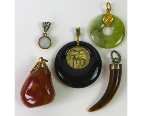 A group of five pendants, comprising a late 20th century jade bi-disk, a similarly shaped jet pendant inset with Chinese good