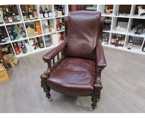 An early Victorian mahogany leather library armchair with turned and carved decoration over turned feet and white ceramic cas