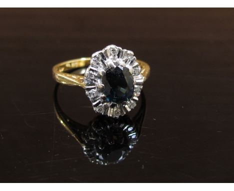 An 18ct gold ring set with central sapphire framed by twelve diamonds. Size J, 3.2g   