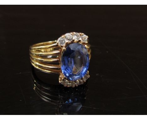 A gold ring with oval synthetic sapphire in multi split shoulders, stamped 9ct. Size K, 5g