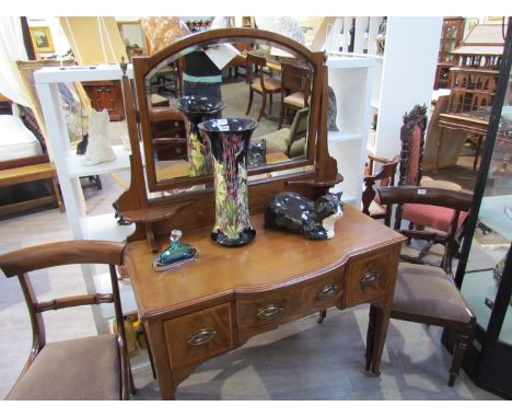 An Edwardian crossbanded mahogany breakfront dressing table the brass finials and tilting bevelled edge mirror over shaped ca