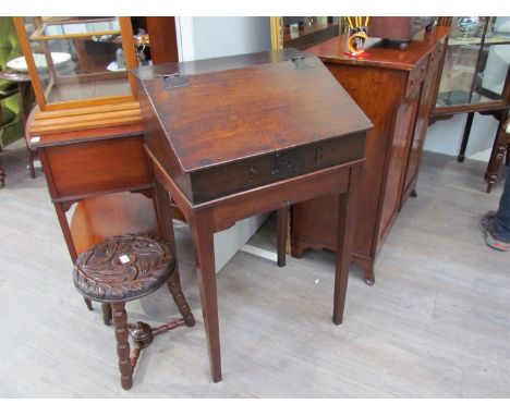 An early 18th Century oak desk on stand the rising slope and shelf interior over square tapering legs with carved central mot