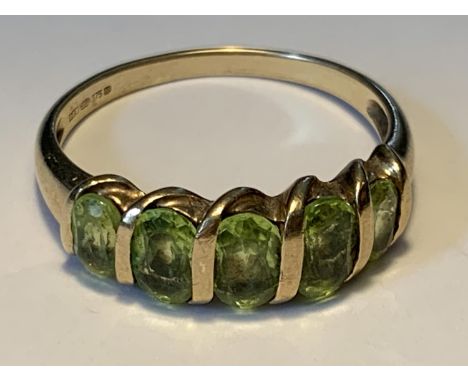 A 9 CARAT GOLD RING WITH FIVE IN LINE PERIDOTS SIZE Q 