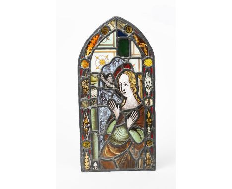 A stained glass panel of The Annunciation,  arched rectangular panel, inside border of grotesque masks, unsigned 56 x 27.5cm.