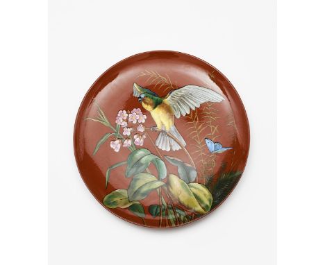 An Aesthetic Movement  Minton's Redware wall charger,  painted with a parrot perched on an exotic flower stem, a blue butterf