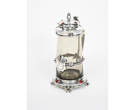 A silver mounted glass tankard and cover, swollen low base on four tapering, scrolled feet, cast in low relief with geometric