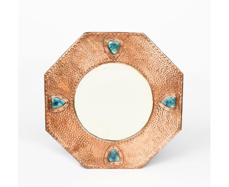 An octagonal copper mirror, hammered finish, applied with four Ruskin  blue ceramic hearts set in riveted copper border, unsi