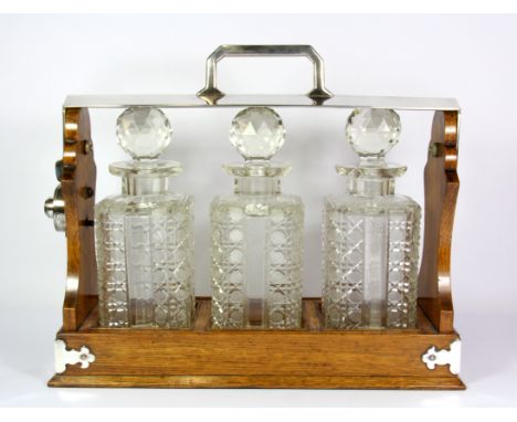 An oak and silver plate tantalus with three cut crystal decanters (one decanter A/F), H. 30cm, W. 36cm.