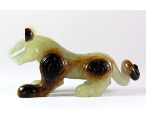 An unusual Chinese russet and celadon carved jade figure of a tiger, probably 19th century, L. 11cm, H. 6cm.