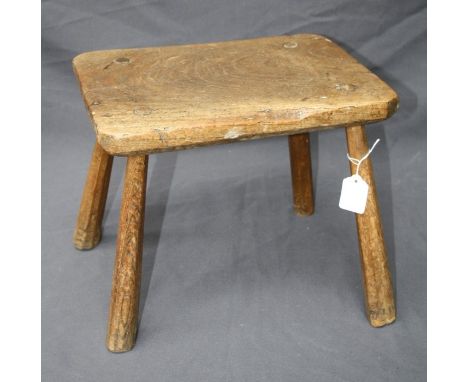 A rustic elm farm stool with hewn legs
