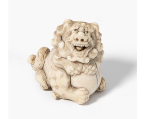 NetsukeJapan, 19.Jh. Elfenbein. Shishi-Löwe, in seinen Pranken eine Kugel haltend. In seinem Maul eine kleine, bewegliche Kug