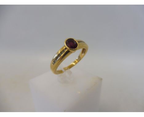 A gold ring set with a central ruby flanked by diamond chip. 