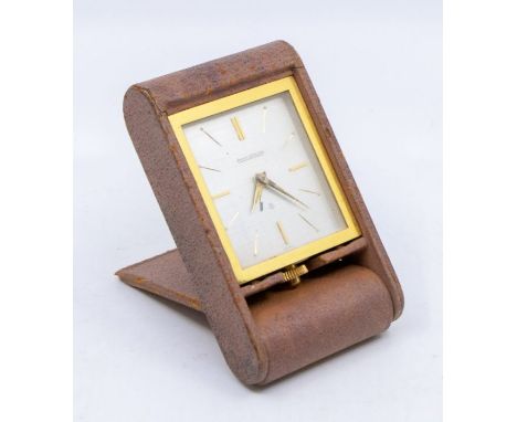 A Jaeger LeCoultre travel alarm clock, rectangular silvered dial with gold baton indicators, in a folding brown leather case,