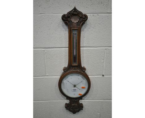 AN EARLY 20TH CENTURY OAK BAROMETER, with scrolled and shell decoration, the thermometer above an 8 inch face, height 82cm (c