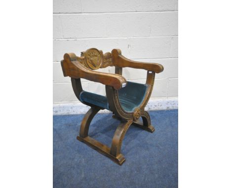 A 20TH CENTURY OAK SAVONAROLA CHAIR, the backrest with foliate carved detail and central shield design, scrolled open armrest