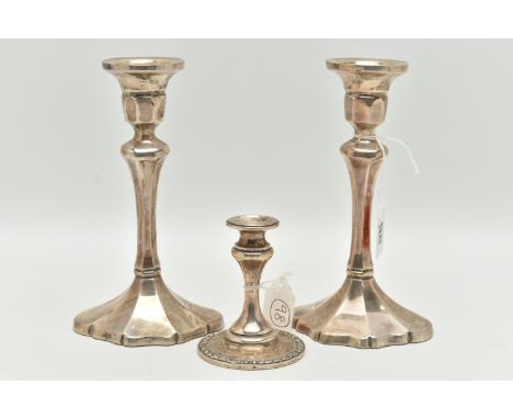 A PAIR OF ELIZABETH II SILVER CANDLESTICKS AND A DWARF CANDLE STICK, the first faceted pair of candlesticks on oval faceted a