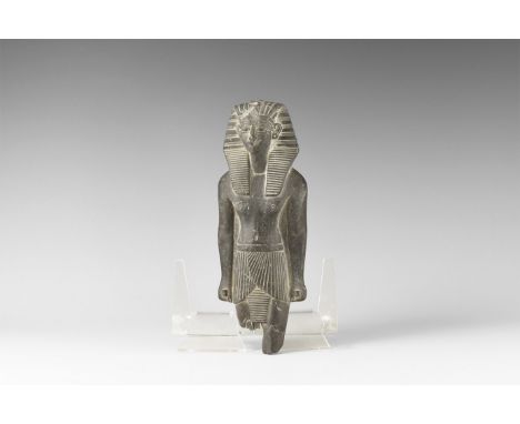 20th century AD. A black stone figure of a striding Pharaoh wearing nemes headcloth with uraeus to the brow, shendyt kilt aro