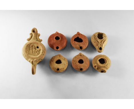 1st-19th century AD. A group of seven terracotta oil lamps consisting of: a round oil lamp with flat top and small lug shaped