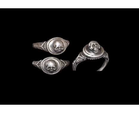 Early 20th century AD. A round-section silver hoop with scrolled flared shoulders, pie-dish bezel with ropework gusset, raise