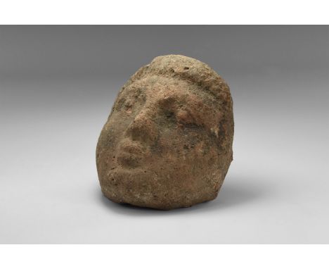 An undated archaistic ceramic antefix of a female head with border of hair at the top, small eyes and pursed lips and with ch