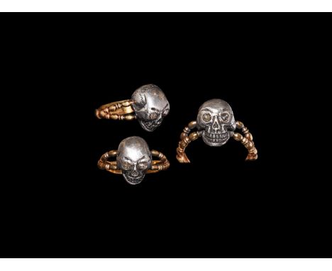 Early 20th century AD. A gold(?) cusped hoop with bifid balustered shoulders, silver(?) bezel of a skull with inset faceted g