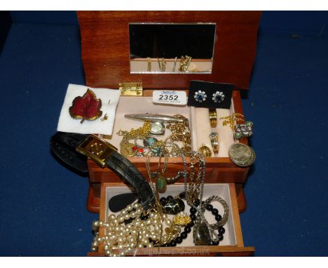 A small wooden jewellery box containing a mixture of costume rings, necklaces, brooches, earrings, etc