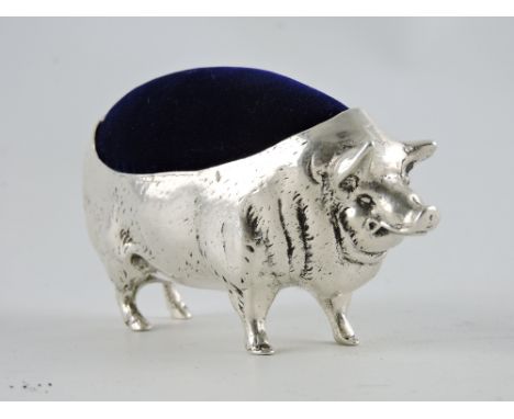 A large white metal pig pin cushion with blue velvet lining
