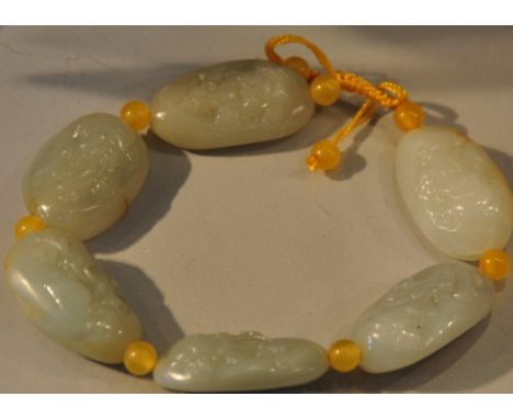 A celadon jade bead bracelet with beads carved into the form of sage's faces