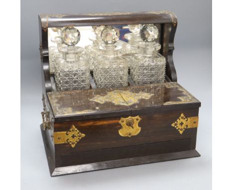A Victorian brass-bound coromandel three-decanter tantalus, fitted twin hinged flaps enclosing a compartmented interior over 