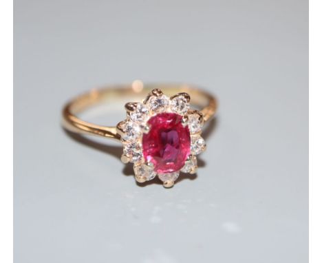 An 18k, ruby and diamond set oval cluster ring, size L, gross 2.9 grams.CONDITION: One of the diamonds has a tiny nick to the