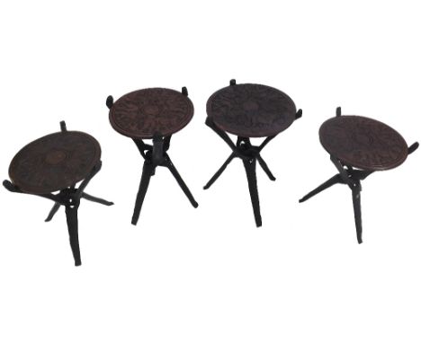 Two pairs of interesting African tribal art tripod tables, the circular tops carved with wildlife upon intertwined ebony type