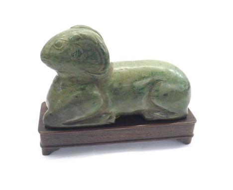 Large mottled Chinese green carved jade modelled as a recumbent ram, upon a hardwood base, 6" long overall