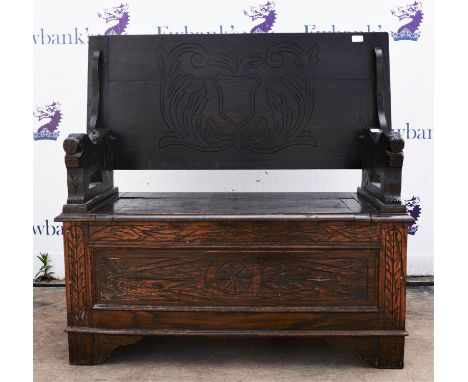 An oak monks bench, 20th Century, with hinged carved top, above carved arms decorated with lions, with hinged seat, on bracke