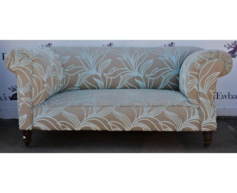 Victorian two seat sofa, with a reclining end, on turned legs terminating with brass casters, upholstered in pale ochre and w