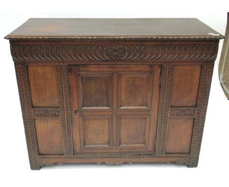 A Carved Oak Cupboard, with a stiff leaf carved border and carved frieze all above a cupboard door with four moulded panels e