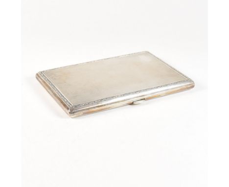 A George V hallmarked silver cigarette case. The Art Deco case having an engine turned pattern with scroll border and vacant 