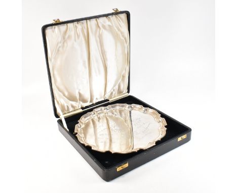 A George IV cased hallmarked silver presentation salver. The salver being of circular form with serpentine rim and having thr