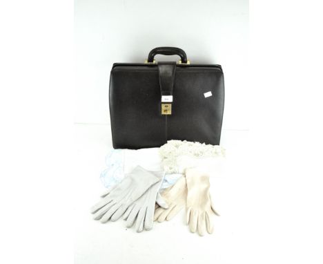A vintage 'Collezione' black leather case with fabric lining, together with two pairs of ladies gloves and two tablecloths