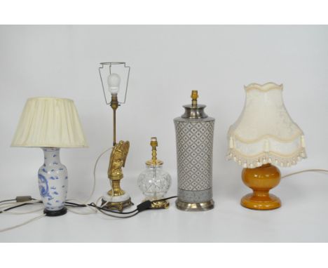 Five table lamps, comprising three ceramic examples with cream shades, a brass lamp modelled as an eagle on a marble base and