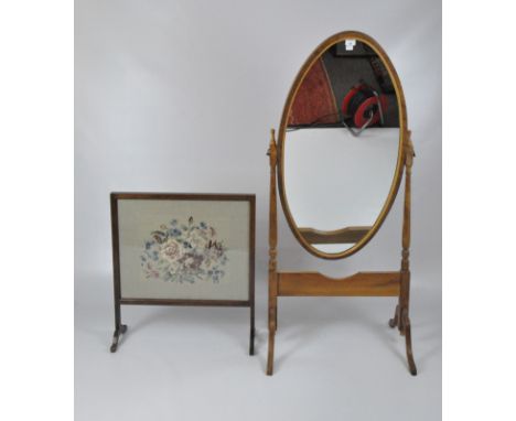 An oval swing mirror on splayed feet, height 144cm; together with a rectangular fire screen with a tapestry of roses behind g