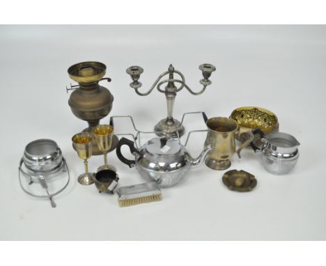 An assortment of metalware, including an oil lamp, candlestick, two glasses, brushes and more