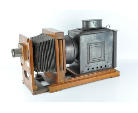 An antique magic lantern projector, the metal body mounted onto a wooden frame, length 60cm