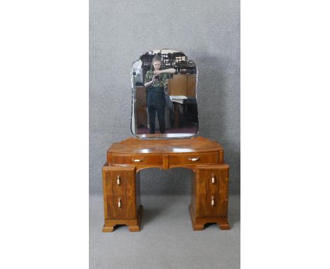 A mid century walnut Art Deco style dressing table with cloud shaped adjustable mirror above six drawers on shaped bracket fe