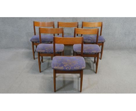 A set of six vintage teak dining chairs with floral upholstered seats on shaped tapering stretchered supports with maker's la