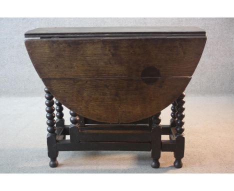 An early 18th century oak drop flap dining table on bobbin turned gateleg supports. H.73 W.120 D.92 cm. 