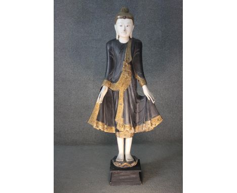 A large early 20th century oriental carved and gilded standing Buddha statue, white painted face, hands and feet, gilded deta