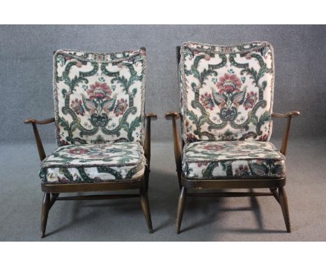 A pair of vintage Ercol beech framed armchairs in cut floral upholstery with maker's label to the underside.