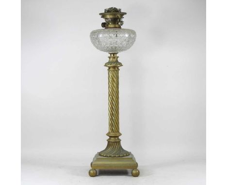 A large 19th century brass oil lamp, having a twisted column, on ball feet, with a hobnail cut clear glass reservoir and Dupl
